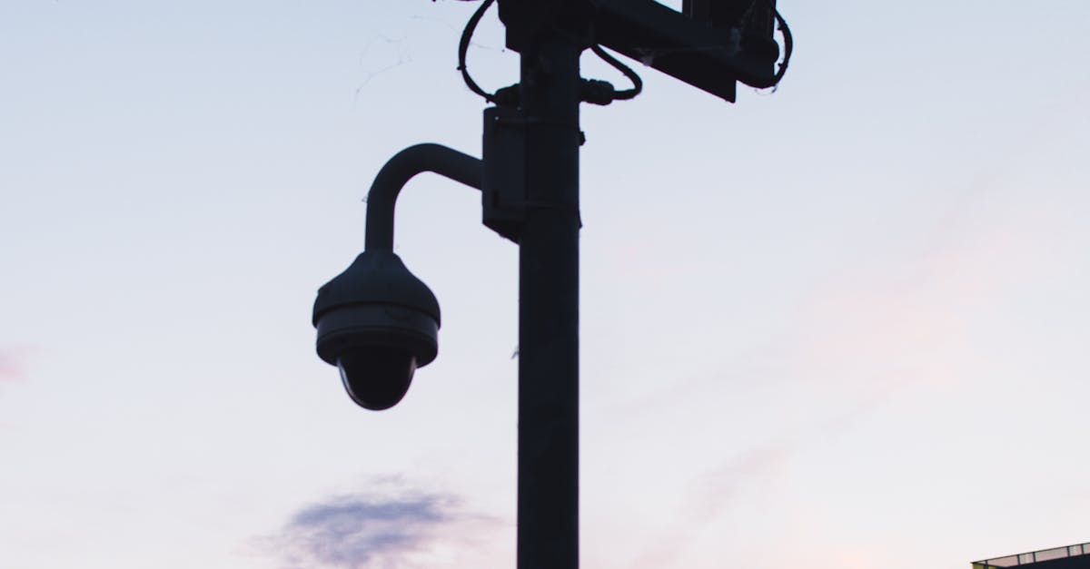 Silhouette of surveillance cameras and streetlights against a beautiful sunset sky.